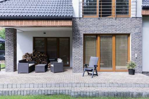 Cobbled terrace behind the modern house, with a set of dark garden furniture